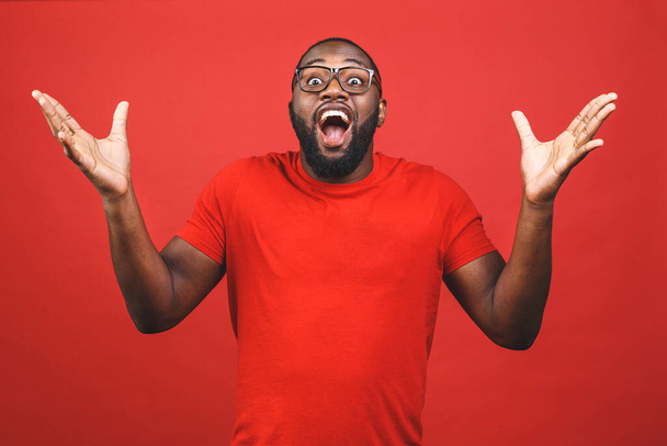 Portret van een opgewonden jonge Afro-Amerikaanse man schreeuwend in shock en verbazing. Verrast zwarte hipster kijkt onder de indruk, kan zijn eigen geluk en succes niet geloven. - Foto, afbeelding