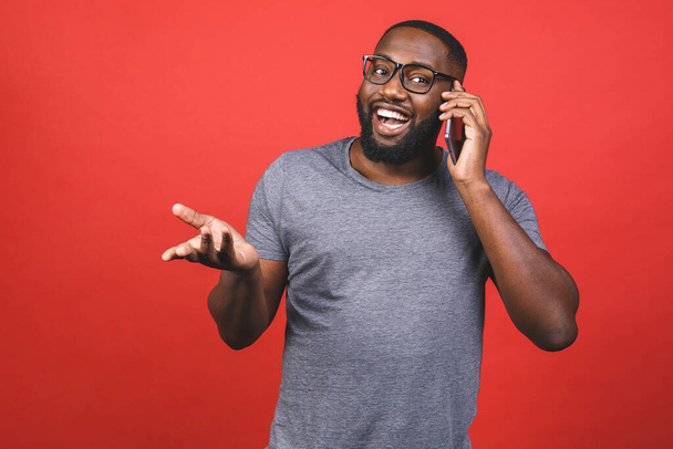 赤い背景から隔離された携帯電話で話す幸せなアフリカ系アメリカ人の男の肖像画.  - 写真・画像