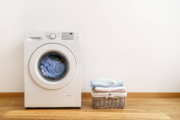Lavadora, gel de lavado y cesta de lavandería sobre fondo blanco
 - Foto, imagen