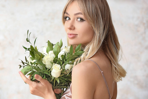 Beautiful young woman with bouquet of roses on light background - Foto, Imagem
