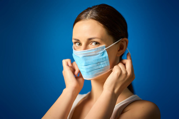 mujer con camisa blanca muestra cómo usar una máscara durante una pandemia
 - Foto, imagen