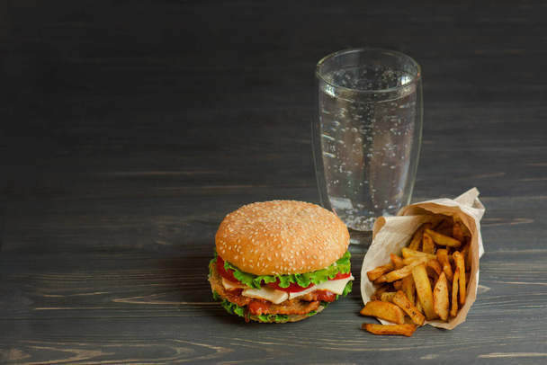 Burger on a rustic wooden board and glass of mineral water - Фото, изображение