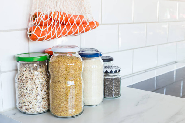 Diferentes alimentos em frascos de vidro reutilizados e um saco de malha na cozinha, zero conceito livre de resíduos de plástico, espaço de cópia
 - Foto, Imagem