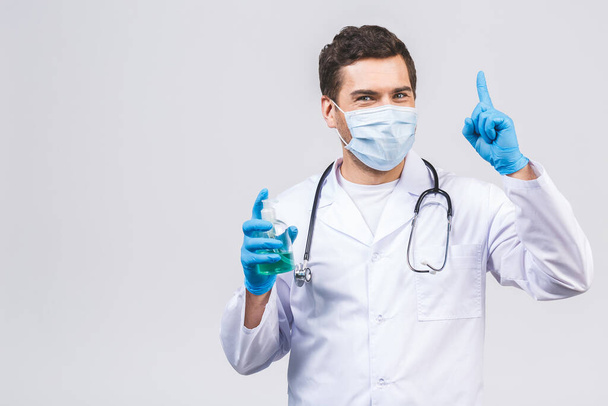 Doctor man in gown face mask gloves isolated on white background. Epidemic pandemic coronavirus 2019-ncov sars covid-19 flu virus. Bottle with alcohol liquid antibacterial sanitizer. - Photo, image