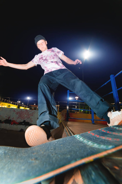A young skater does the trick of sliding at night in a skatepark. The concept of night leisure and youth culture at night - Φωτογραφία, εικόνα