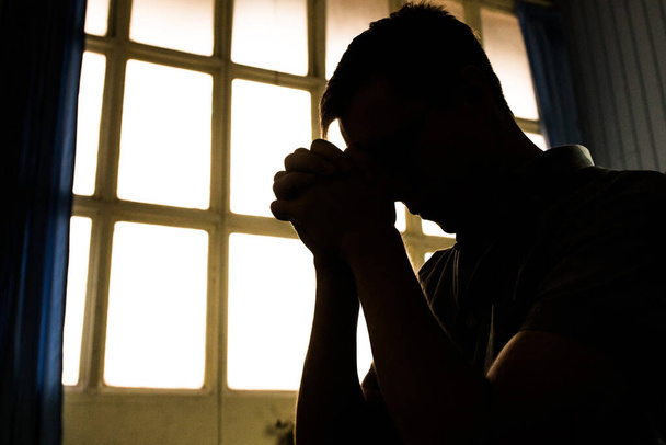 Dikdörtgen pencere çerçeveleriyle dua eden bir adamın silueti - Fotoğraf, Görsel