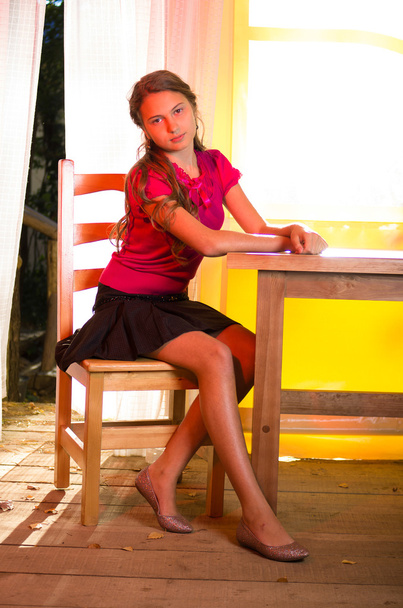 jeune fille assise près de la table en bois
 - Photo, image