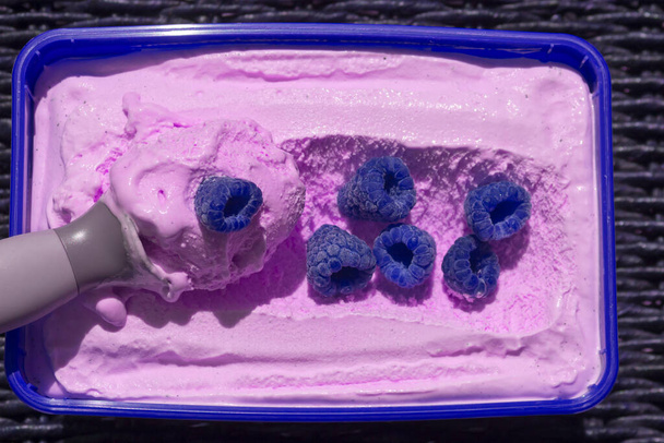 Blue box of pink ice cream with a scoop and berries - Photo, Image