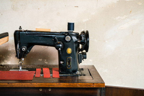 Velha máquina de costura pedal vintage com parede de cimento grungy rústico
 - Foto, Imagem