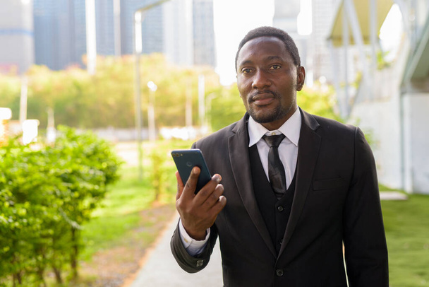 Πορτρέτο του όμορφος γενειοφόρος αφρικανός επιχειρηματίας με κοστούμι χαλάρωση στο πάρκο στην ύπαιθρο της πόλης - Φωτογραφία, εικόνα