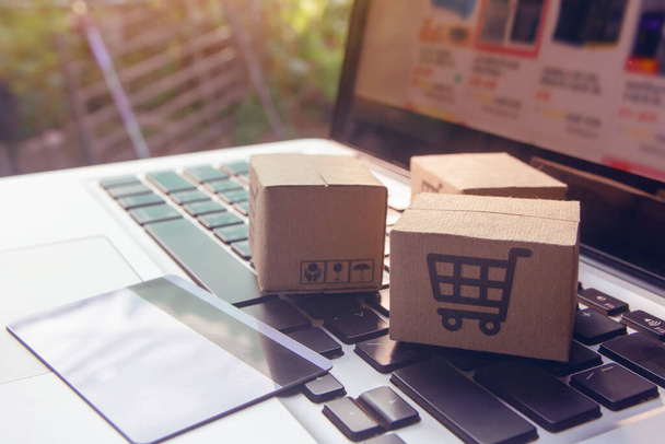 Online vásárlás - Papírdobozok vagy csomagok bevásárlókosár logóval és hitelkártyával egy laptop billentyűzeten. Bevásárlási szolgáltatás az online weben, és kínál házhozszállítás - Fotó, kép