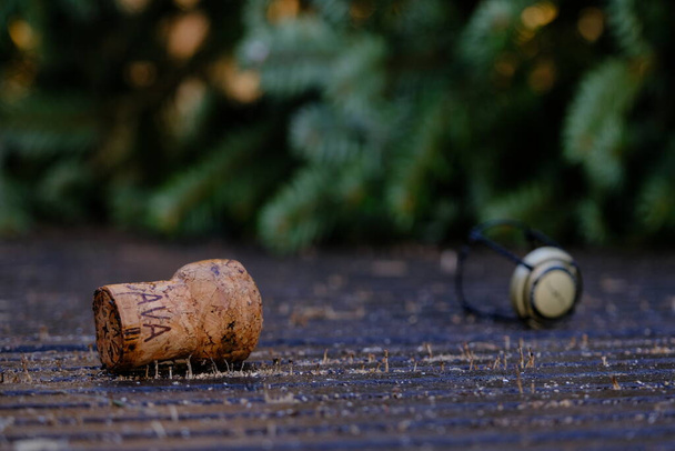Закройте пробку из бутылки шампанского на фоне неострой сосны. Темная сцена на влажном деревянном полу
. - Фото, изображение