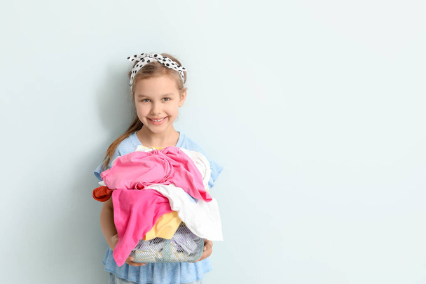 Little girl with dirty laundry on light background - Фото, зображення