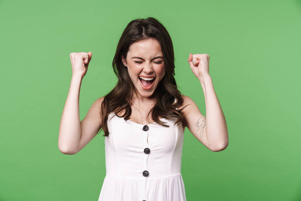Image of delighted attractive woman screaming and making winner gesture isolated over green background - Foto, Imagem
