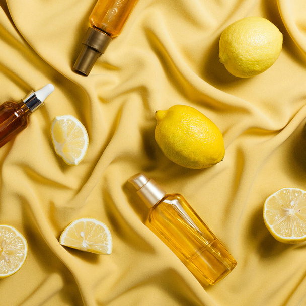 Flatlay of lemons and various vitamin C cosmetic product on yellow drapery - Fotografie, Obrázek
