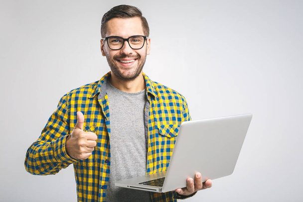 Selbstbewusster Wirtschaftsexperte. Selbstbewusster junger gutaussehender Mann im Hemd, Laptop in der Hand und lächelnd vor weißem Hintergrund - Foto, Bild