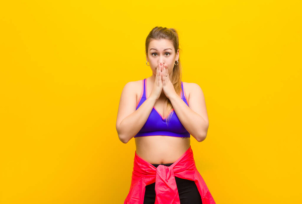 young blonde woman feeling worried, upset and scared, covering mouth with hands, looking anxious and having messed up. sport concept - Photo, Image