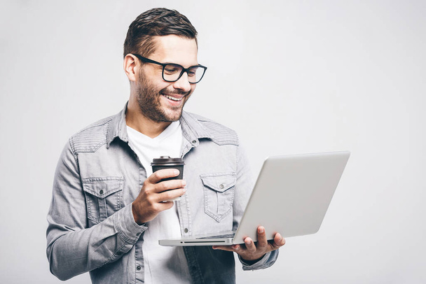 Expert en affaires confiant. Confiant jeune bel homme en chemise tenant ordinateur portable et souriant tout en se tenant debout sur fond blanc
. - Photo, image
