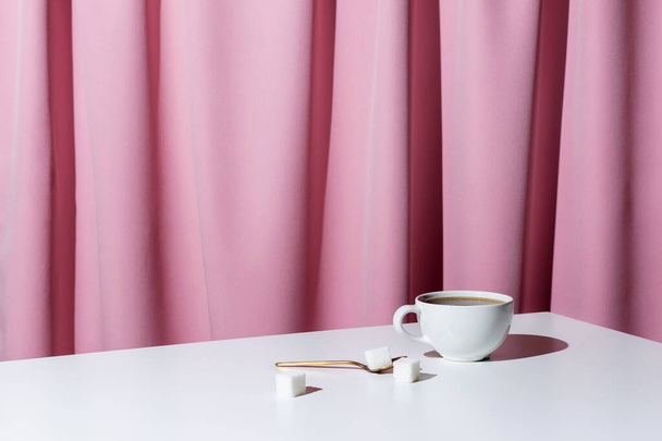 Cup of tea or coffee on white table in front of pink drapery, selective focus - Foto, afbeelding
