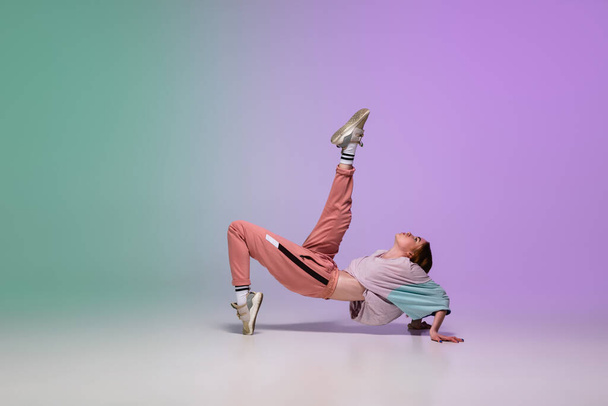 Girl dancing hip-hop in stylish clothes on gradient background at dance hall in neon light. - 写真・画像