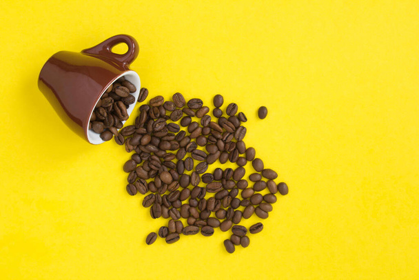 Brown ceramic cup with coffee beans  on the  yellow background. Copy space. Top view. - Photo, Image