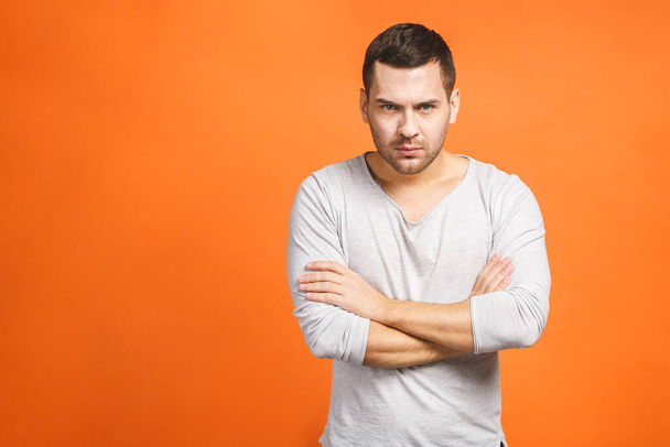 Image of angry displeased man standing isolated over orange background wall. Looking at camera. - Foto, Imagem