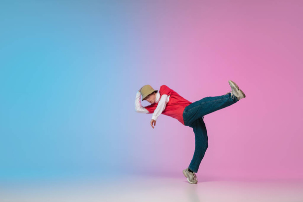 Boy dancing hip-hop in stylish clothes on gradient background at dance hall in neon light. - Fotografie, Obrázek