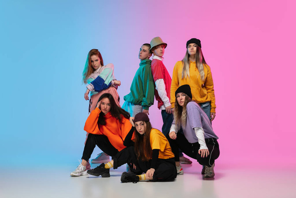 Group of dancers, boys and girls dancing hip-hop in stylish clothes on gradient studio background in neon light. - Zdjęcie, obraz