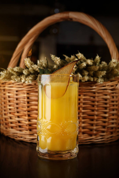 Ein Glas Birnensaft auf dem Hintergrund eines Weidenkorbs - Foto, Bild