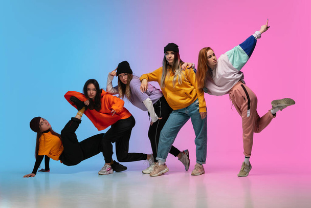 Group of dancers, boys and girls dancing hip-hop in stylish clothes on gradient studio background in neon light. - Fotoğraf, Görsel