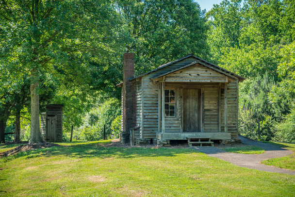 A rustic wooden cabin with a outhouse closeup with trees surrounding the building on a bright sunny day in summertime - Photo, Image