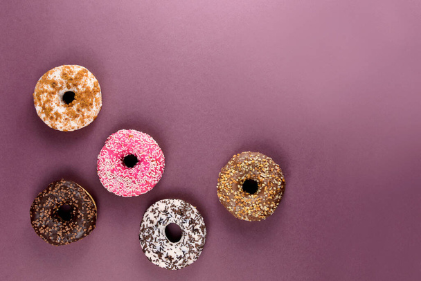 Different donuts on a brown background top view stock images. Different donuts isolated on a brown background with copy space for text. Doughnut frame stock images - Photo, Image