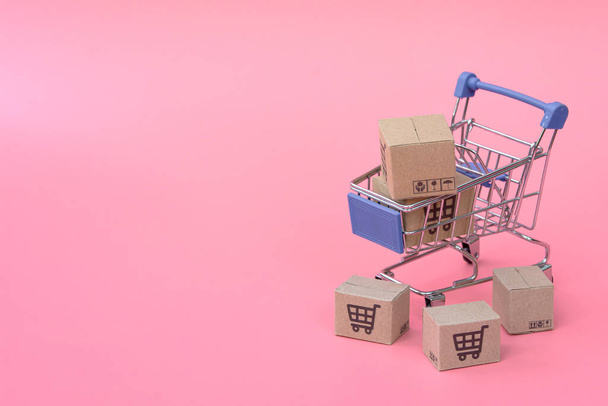 ショッピングのコンセプト:ピンクの背景に青いショッピングカートのカートンまたはペーパーボックス。オンラインショッピングの消費者は自宅や宅配サービスから買い物ができます。spacをコピーして - 写真・画像
