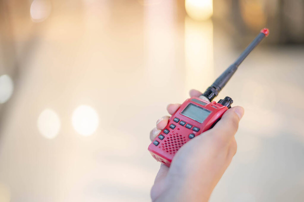 La mano maschile con un walkie talkie rosso o un ricetrasmettitore radio portatile per la comunicazione
. - Foto, immagini