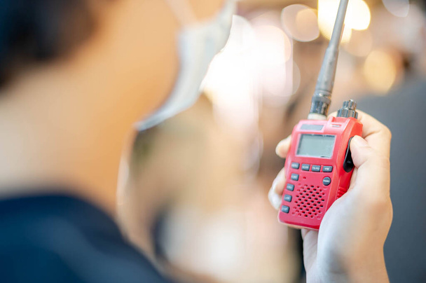La main mâle tenant avec un talkie-walkie rouge ou émetteur-récepteur radio portable pour la communication
. - Photo, image