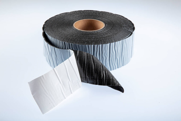 Black industrial tape in roll on white background. Rubber insulating tape. Sound insulation adhesive tape. - Photo, Image