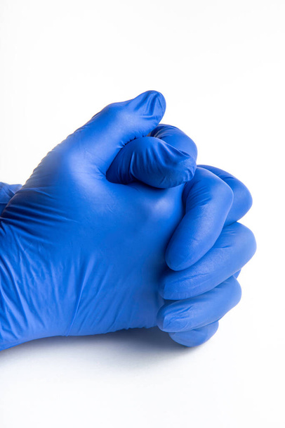Mains portant des gants jetables en latex bleu sur fond blanc uni
. - Photo, image