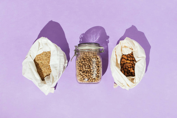 Zero-waste healthy grocery shopping concept: chickpeas, brown rice, almonds in mesh net bags and glass jar - Fotografie, Obrázek