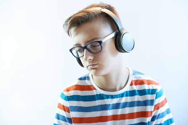 Sad teen boy listens to music on headphones - Fotó, kép