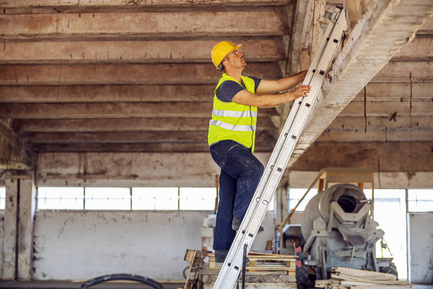 Bauarbeiter klettert auf Leiter und bereitet Dachreparatur vor. - Foto, Bild