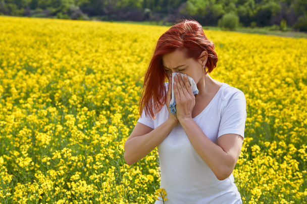 Alergický na pyl a kvetoucí období, dívka kýchne na květinové pole - Fotografie, Obrázek