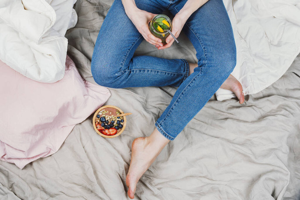 Above shot of woman sitting on a bed with healthy breakfast on side - Φωτογραφία, εικόνα