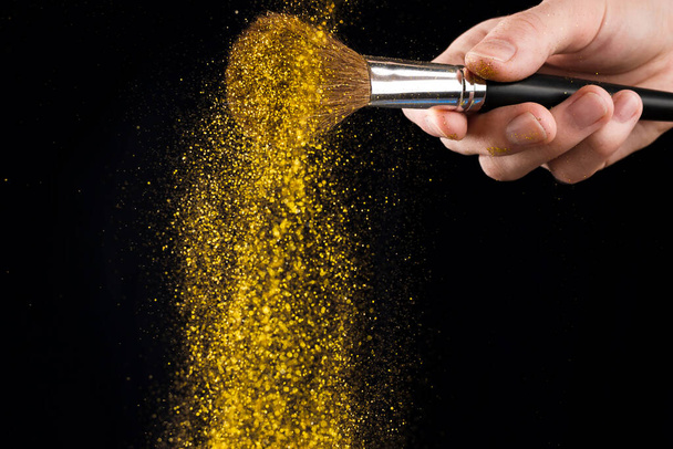 Closeup of woman's hand holding make-up brush with sparking shining glitter, selective focus - Φωτογραφία, εικόνα