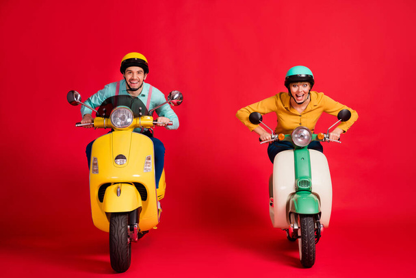 Portrait of his he her she nice attractive crazy cheerful cheery glad positive couple driving moped having fun rally race fast speed isolated over bright vivid shine vibrant red color background - 写真・画像