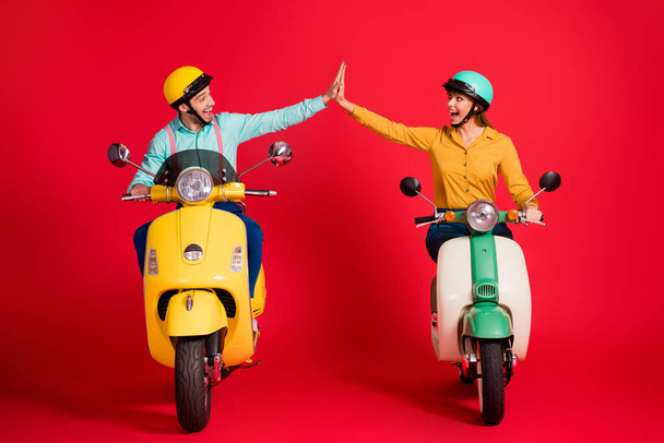 Portrait of his he her she nice attractive lovely glad lucky ecstatic cheerful cheery couple riding moped giving high five having fun isolated over bright vivid shine vibrant red color background - Foto, Bild