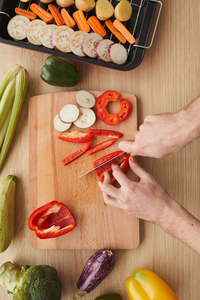 Man cutting vegetables on cutting board - Фото, зображення