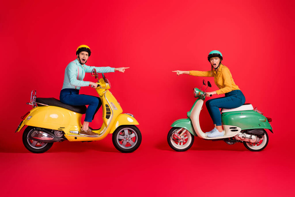 Profile side view of his he her she nice attractive funny outraged couple riding moped pointing at each other blaming isolated over bright vivid shine vibrant red color background - Foto, Imagem
