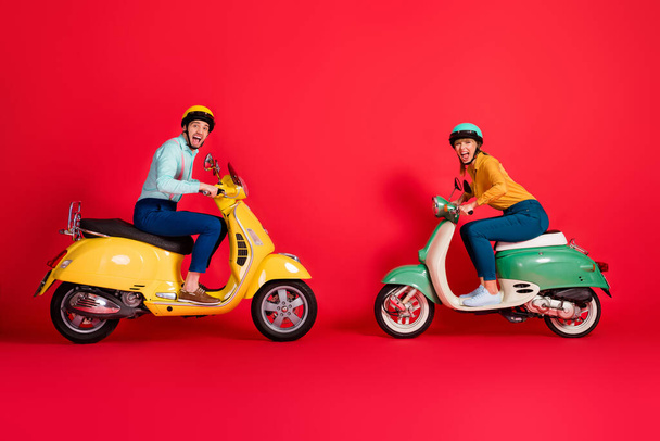 Profile side view of nice attractive crazy ecstatic overjoyed cheerful cheery couple driving moped opposite having fun rivalry isolated on bright vivid shine vibrant red color background - Fotó, kép