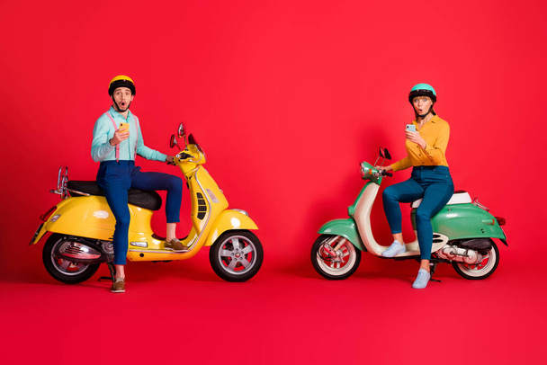 Full length body size view of her she his he nice attractive amazed stunned friends friendship sitting on moped using 5g web service app isolated on bright vivid shine vibrant red color background - Фото, изображение