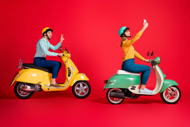 Profile side view of her she his he nice attractive cheerful friends friendship riding moped taking selfie showing v-sign having fun isolated on bright vivid shine vibrant red color background - Foto, afbeelding
